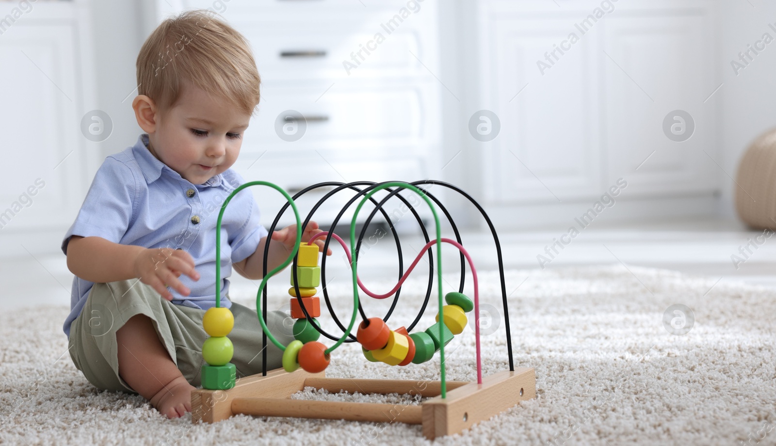 Cute little baby playing with toy on floor at home, space for text Photo of Cute little baby playing with toy on floor at home, space for text