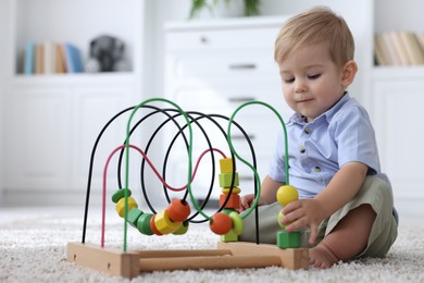Photo of Cute little baby playing with toy on floor at home