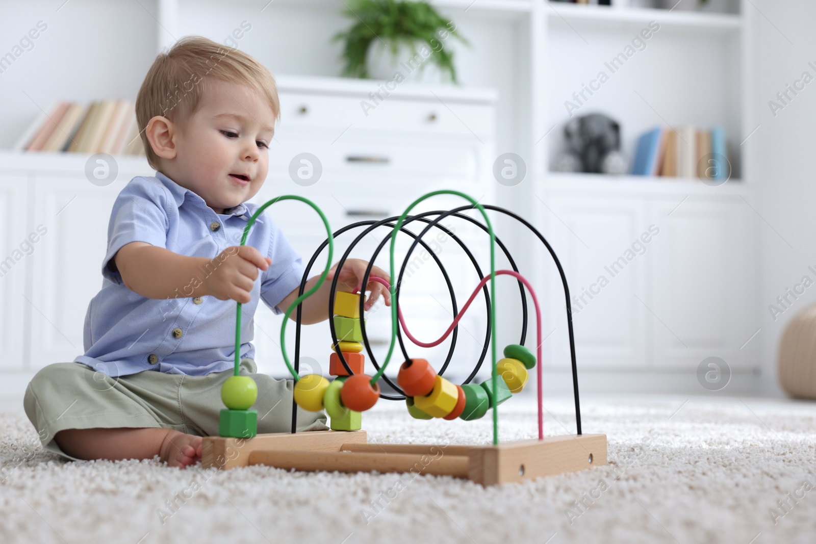 Cute little baby playing with toy on floor at home Photo of Cute little baby playing with toy on floor at home