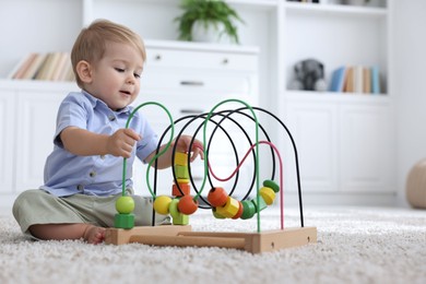 Photo of Cute little baby playing with toy on floor at home