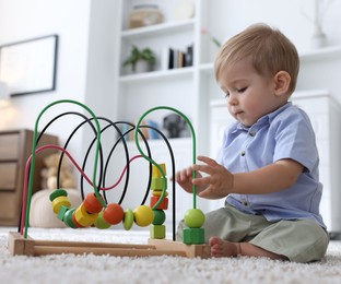 Photo of Cute little baby playing with toy on floor at home