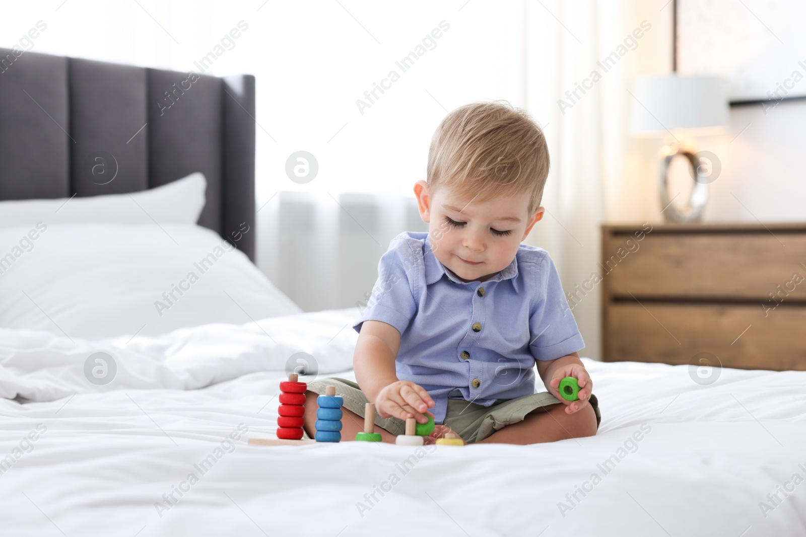 Photo of Cute little baby playing with toy on bed at home