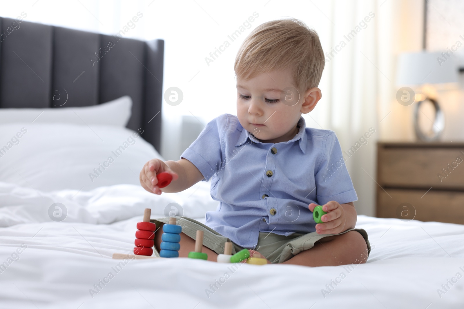 Cute little baby playing with toy on bed at home Photo of Cute little baby playing with toy on bed at home