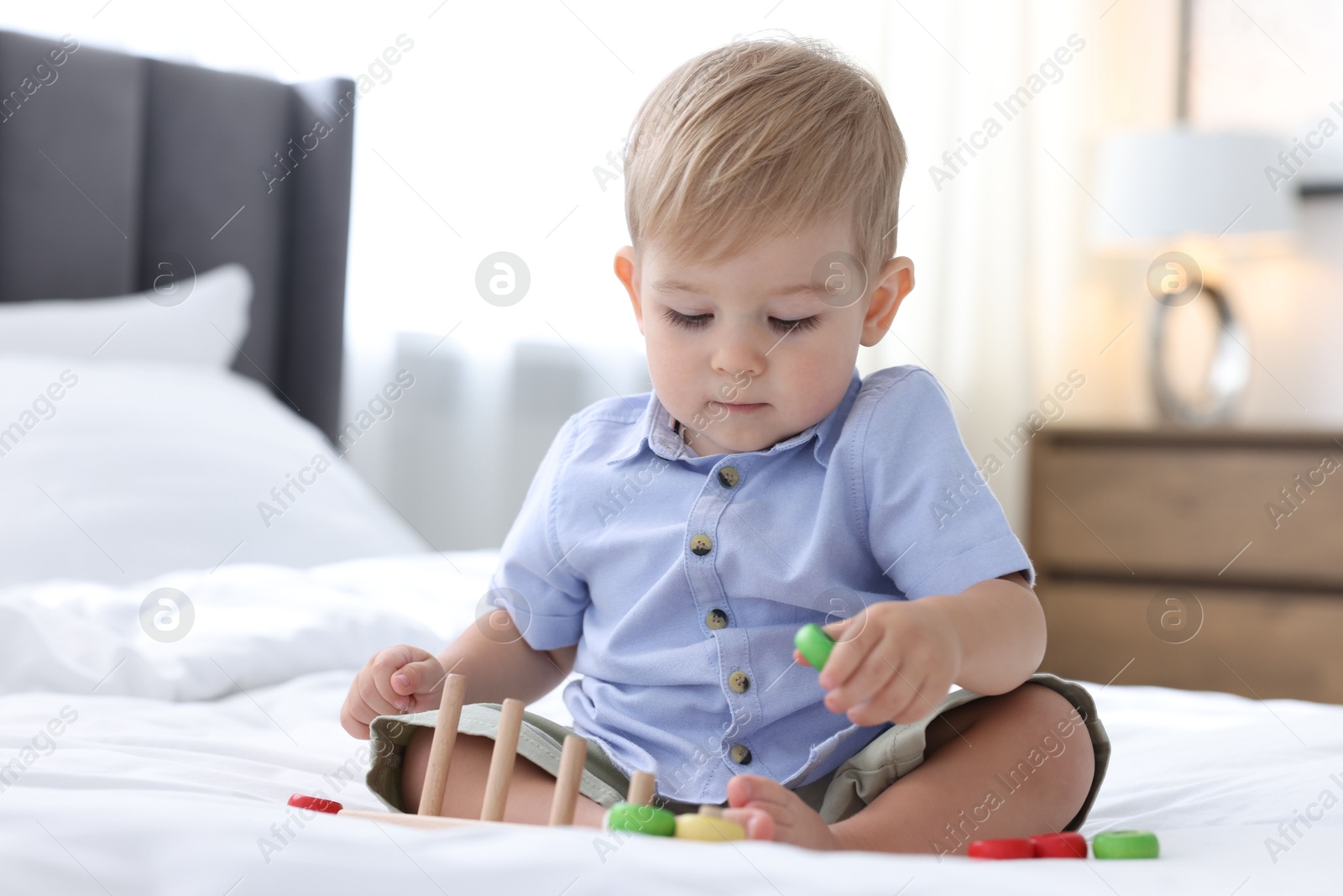 Photo of Cute little baby playing with toy on bed at home