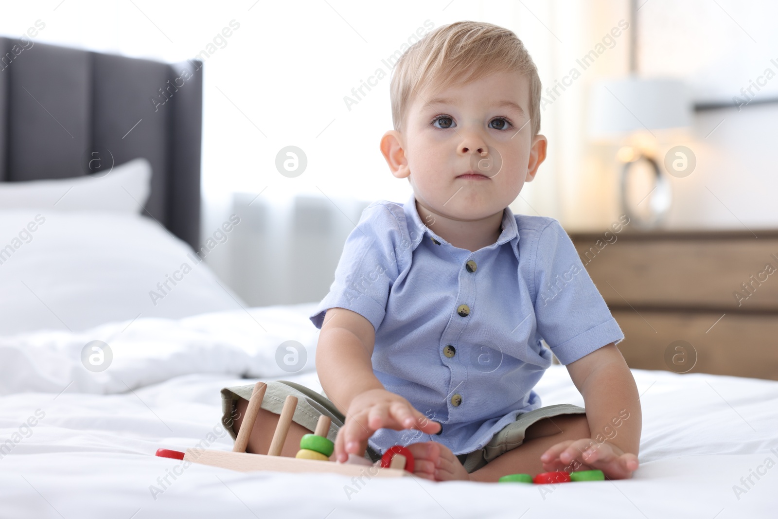 Photo of Cute little baby playing with toy on bed at home