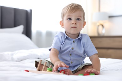 Photo of Cute little baby playing with toy on bed at home