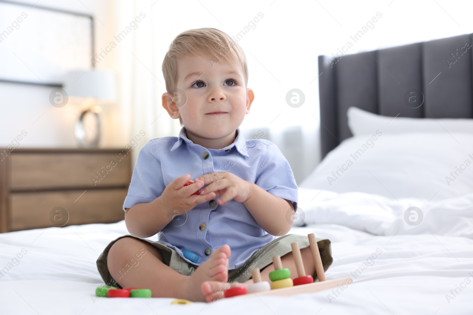 Photo of Cute little baby playing with toy on bed at home