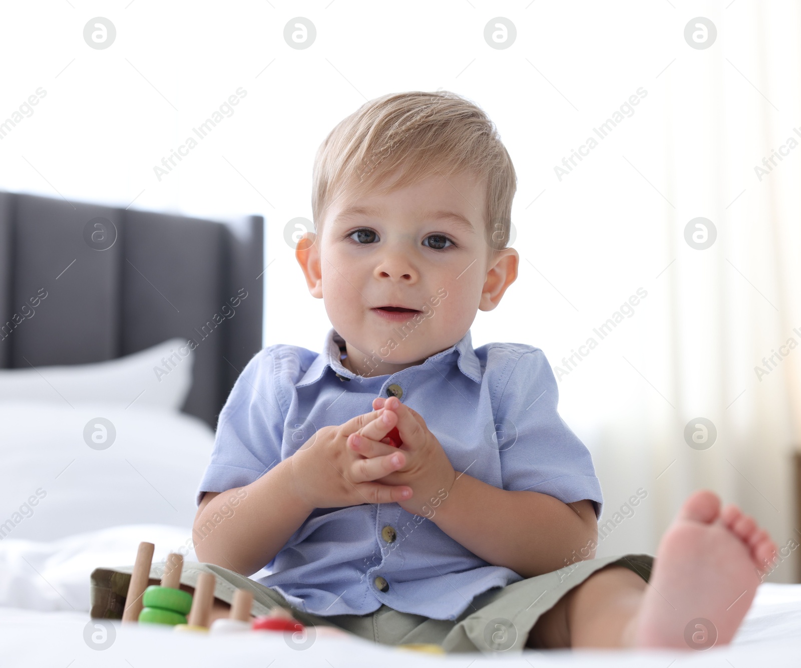 Photo of Cute little baby playing with toy on bed at home