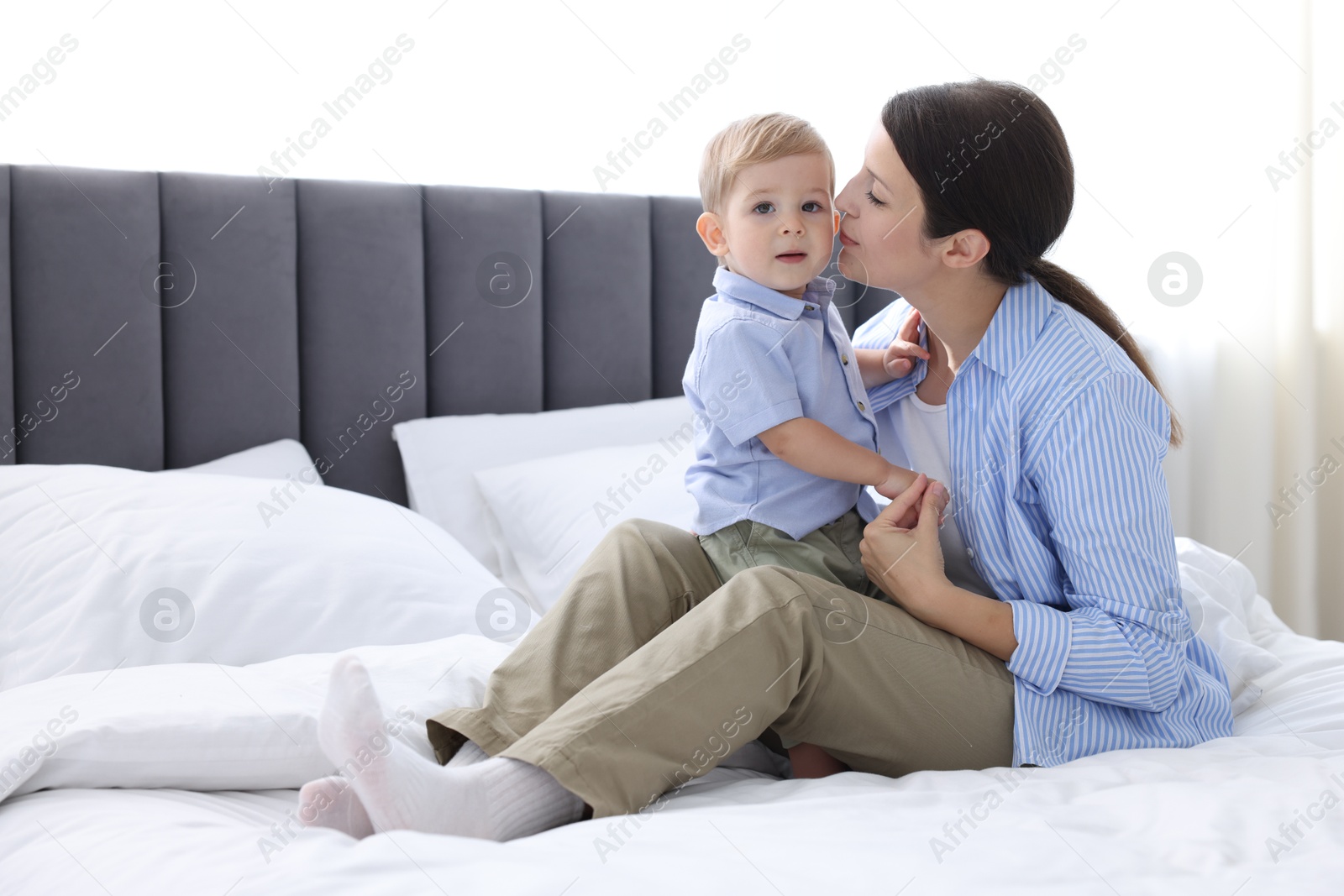 Photo of Mother with her cute little baby on bed at home