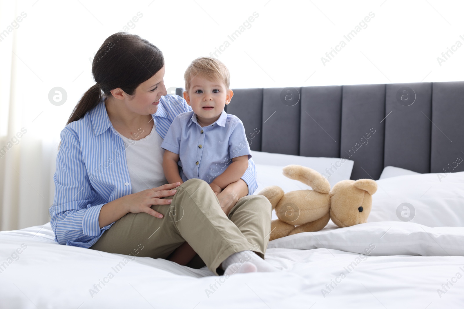 Photo of Mother with her cute little baby on bed at home