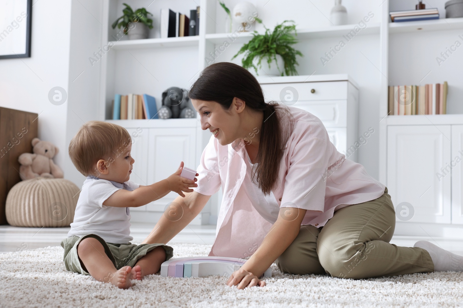 Photo of Mother and her cute little baby playing with toy on floor at home