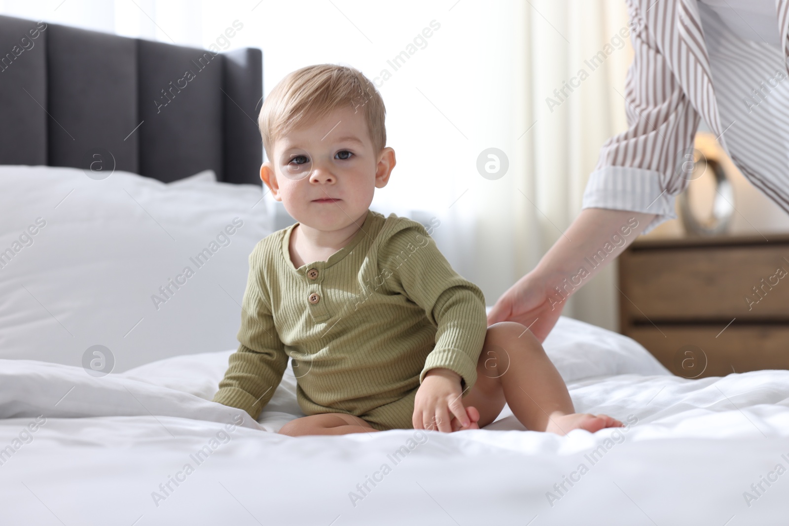 Photo of Mother with her cute little baby on bed at home, closeup