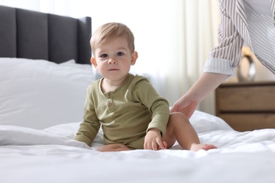 Photo of Mother with her cute little baby on bed at home, closeup