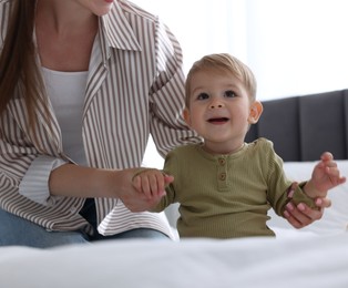 Photo of Mother with her cute little baby on bed at home, closeup