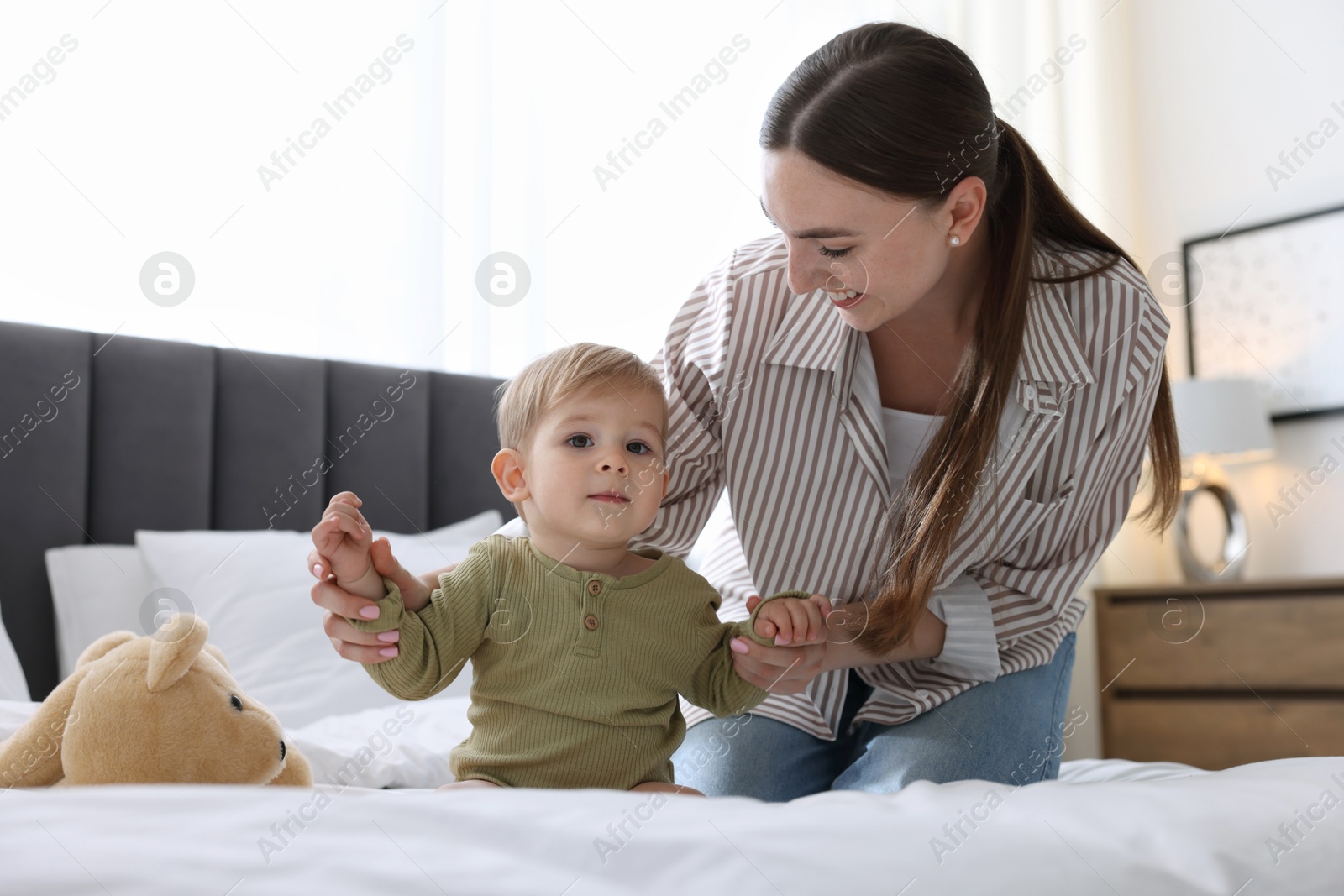 Mother with her cute little baby on bed at home Photo of Mother with her cute little baby on bed at home