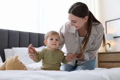 Photo of Mother with her cute little baby on bed at home
