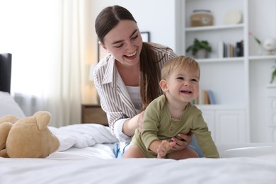 Photo of Mother with her cute little baby on bed at home