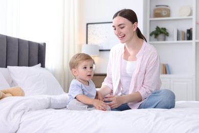 Photo of Mother with her cute little baby on bed at home