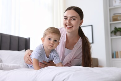Photo of Mother with her cute little baby on bed at home