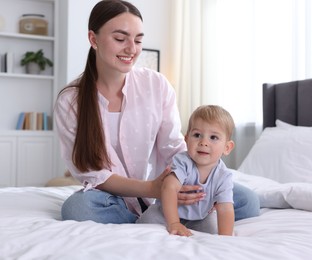 Photo of Mother with her cute little baby on bed at home