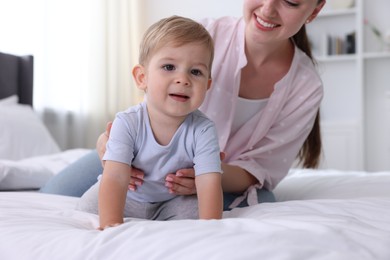 Photo of Mother with her cute little baby on bed at home, closeup