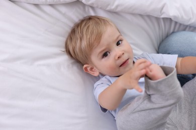 Photo of Cute little baby on bed at home, above view. Space for text