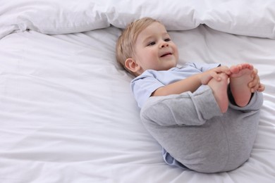 Photo of Cute little baby on bed at home, above view. Space for text