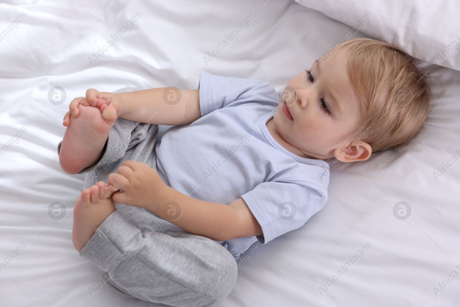 Cute little baby on bed at home, above view Photo of Cute little baby on bed at home, above view