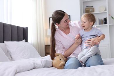 Photo of Mother with her cute little baby on bed at home, space for text