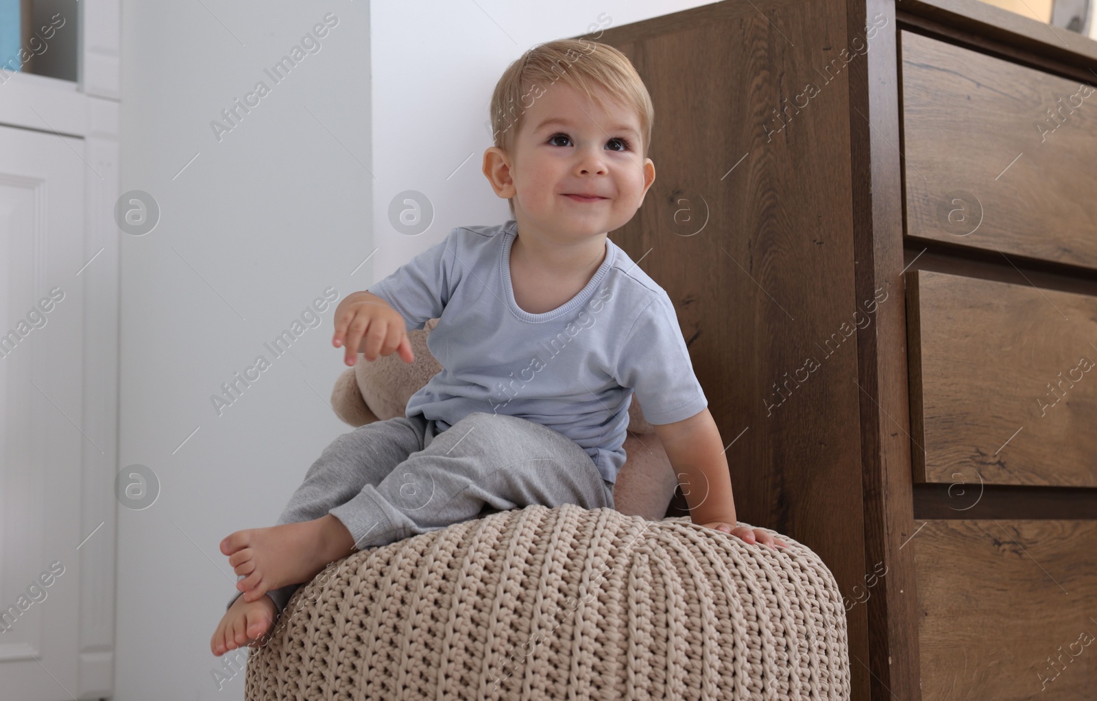 Photo of Cute little baby on pouf at home