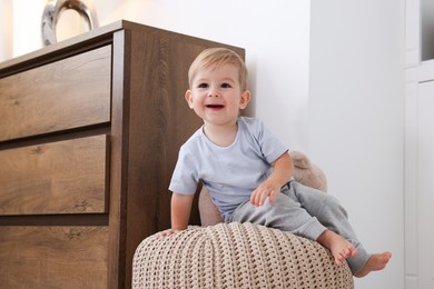 Photo of Cute little baby on pouf at home