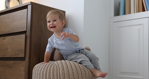 Photo of Cute little baby on pouf at home