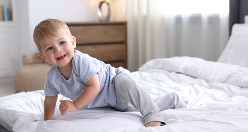 Photo of Cute little baby on bed at home, space for text