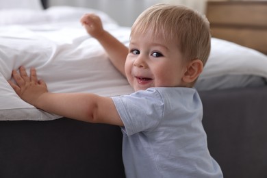 Photo of Cute little baby near bed at home