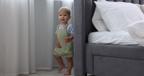 Photo of Cute little baby near bed at home