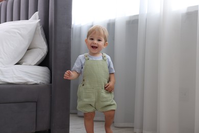 Photo of Cute little baby near bed at home