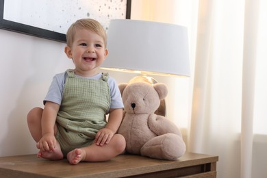 Photo of Cute little baby and toy on wooden dresser indoors, space for text