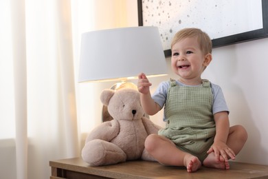 Photo of Cute little baby and toy on wooden dresser indoors, space for text