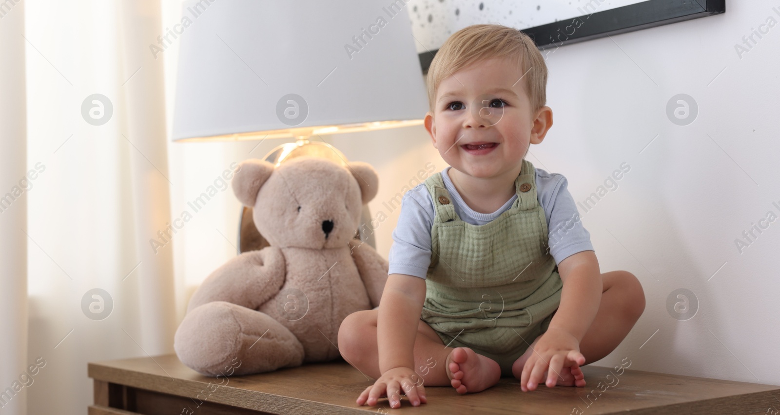 Cute little baby and toy on wooden dresser indoors Photo of Cute little baby and toy on wooden dresser indoors