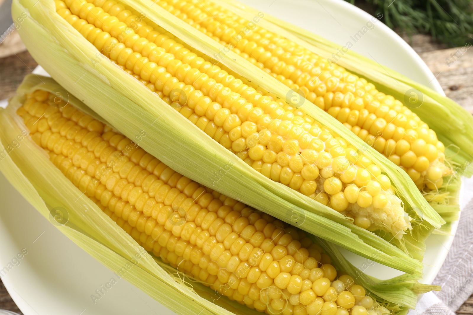 Tasty boiled corncobs on wooden table, closeup Photo of Tasty boiled corncobs on wooden table, closeup
