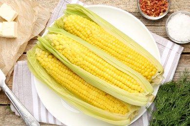 Photo of Tasty boiled corncobs, dill and spices on wooden table, flat lay