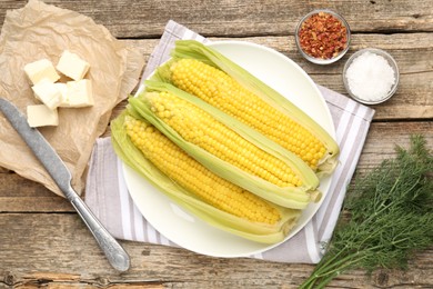 Photo of Tasty boiled corncobs, dill and spices on wooden table, flat lay