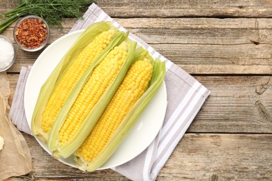 Photo of Tasty boiled corncobs, dill and spices on wooden table, flat lay. Space for text