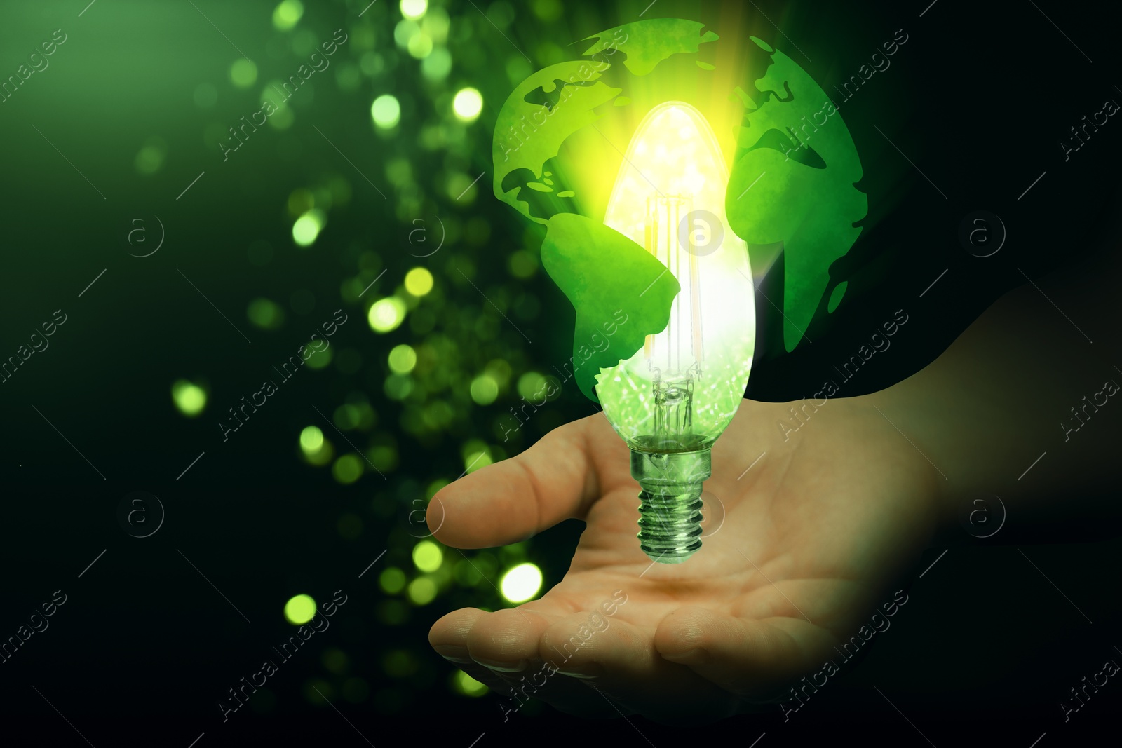 Electricity and nature. Man holding globe with glowing light bulb inside against green gradient background, closeup Image of Electricity and nature. Man holding globe with glowing light bulb inside against green gradient background, closeup