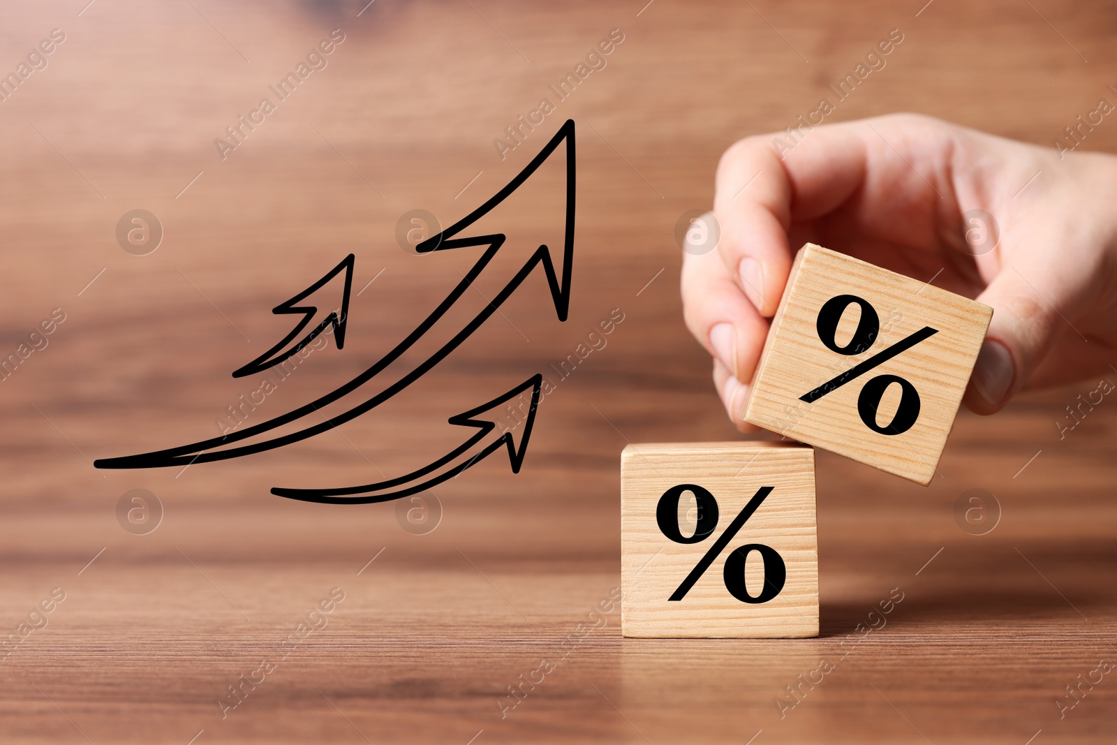 Image of Man holding wooden cube with percent sign at table, closeup