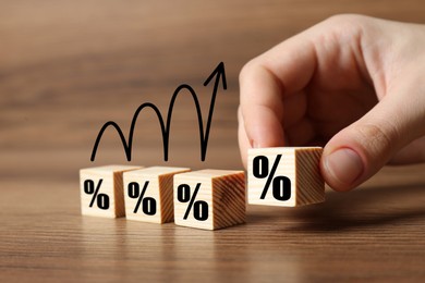 Image of Man putting wooden cube with percent sign next to others at table, closeup