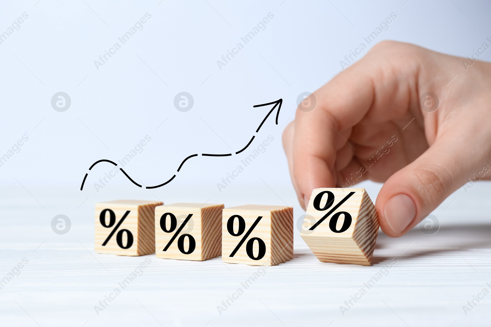 Man holding wooden cube with percent sign at white table, closeup Image of Man holding wooden cube with percent sign at white table, closeup