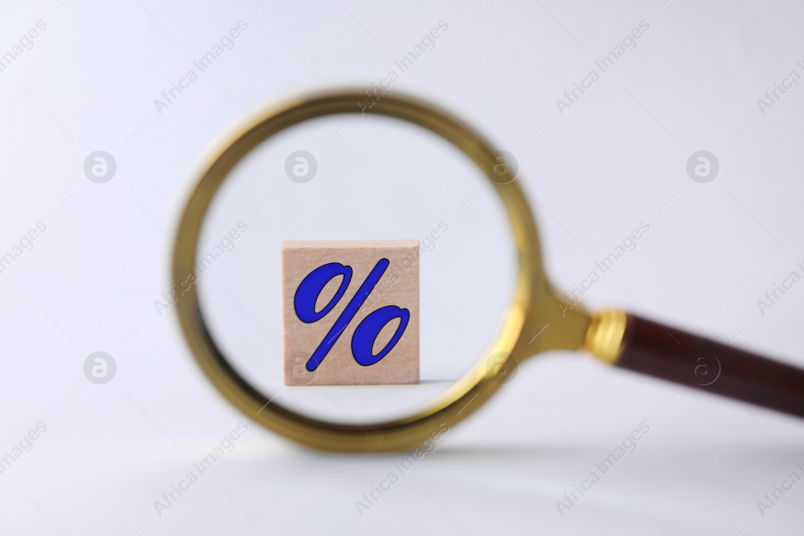 Image of Percent sign on wooden cubes against light background, view through magnifying glass