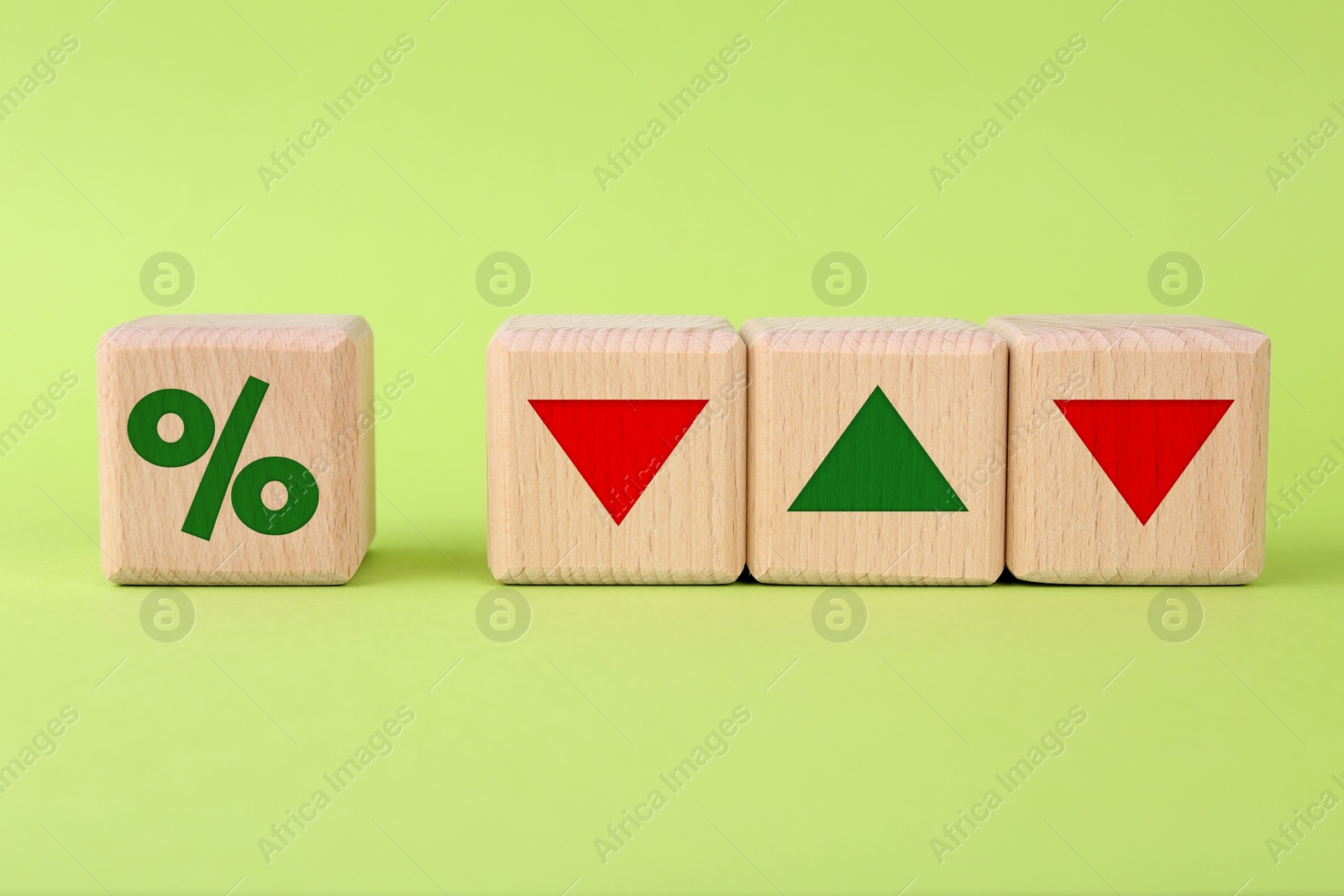 Percent sign, up and down arrows on wooden cubes against light green background Image of Percent sign, up and down arrows on wooden cubes against light green background