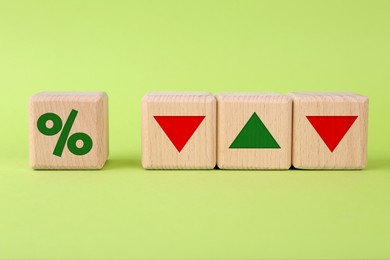 Image of Percent sign, up and down arrows on wooden cubes against light green background